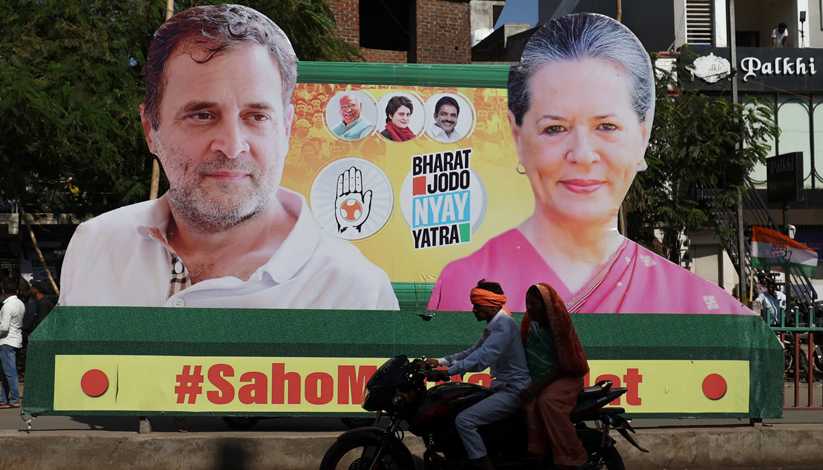 A couple on a motorcycle rides past a banner with the pictures of Rahul Gandhi and Sonia Gandhi, senior leaders of Indias main opposition party, Indian National Congress, on a road during Rahuls 66-day long Bharat Jodo Nyay Yatra, or Unite India Justice March, in Jhalod town, Gujarat state, India, March 7, 2024. &mdash; Reuters