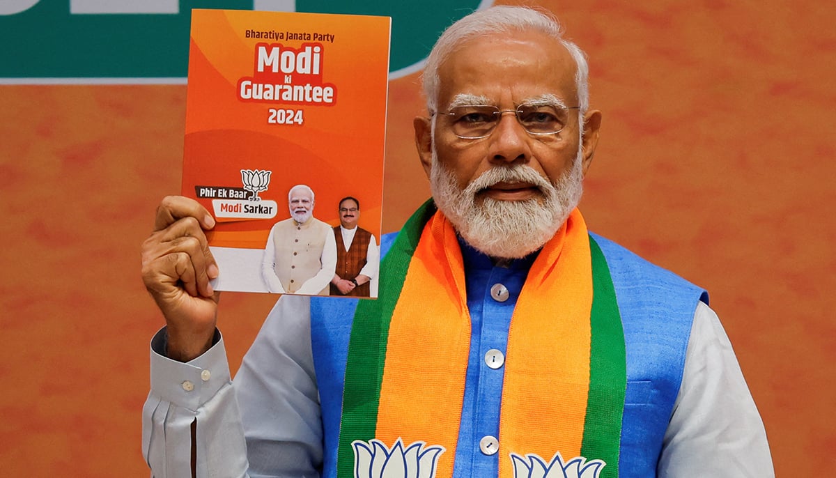 Indian Prime Minister Narendra Modi displays a copy of the ruling Bharatiya Janata Partys election manifesto for the general election, in New Delhi, India, April 14, 2024. &mdash; Reuters