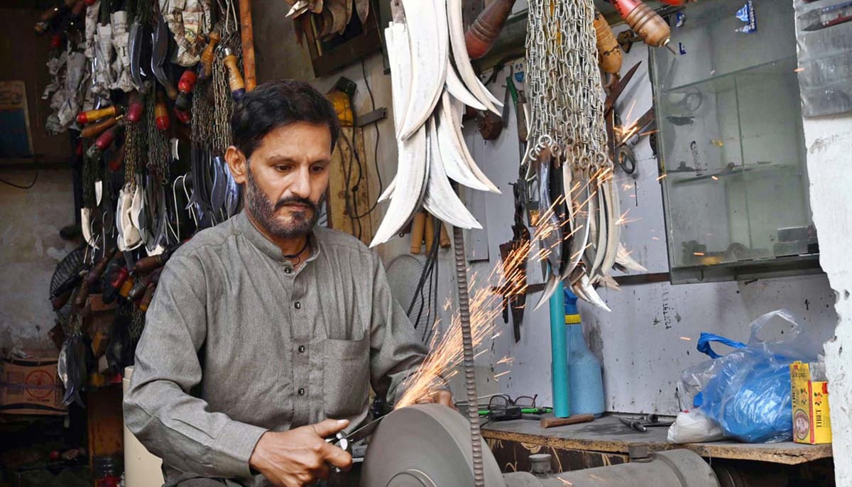 A blacksmith sharpens knives to be used during the procession of Muharram in Lahore on July 14, 2024. — APP