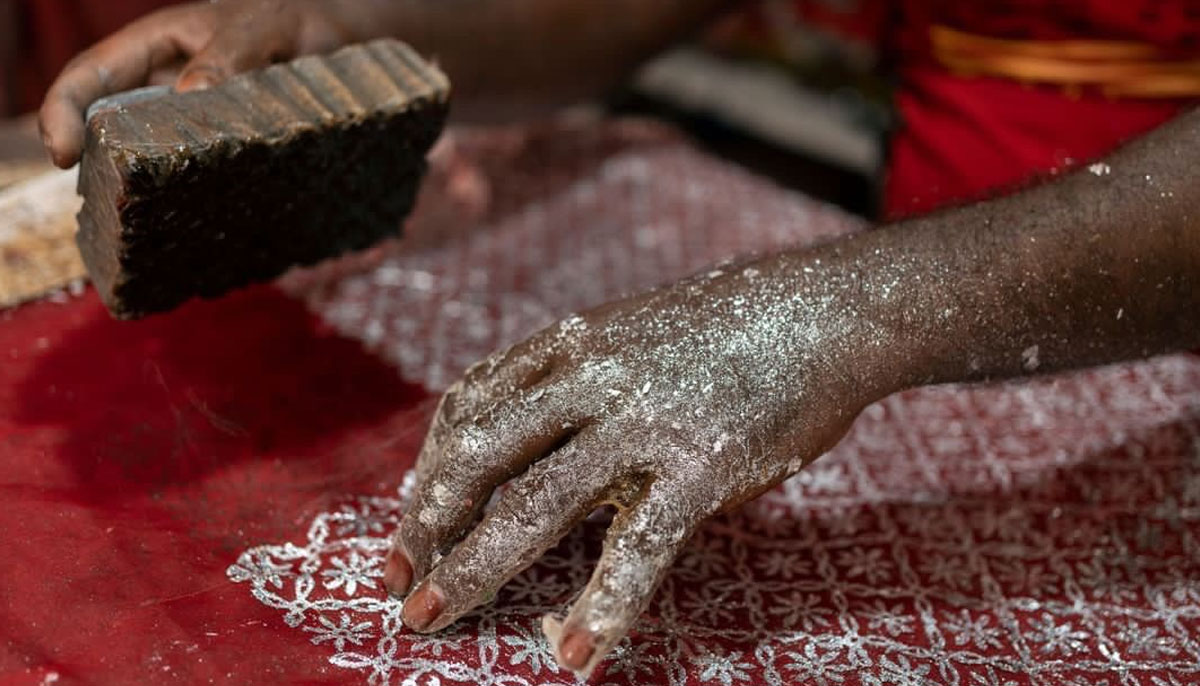 An artisan making chaapa on a red-coloured fabric using a wooden block in Bihar, India. &mdash; Photo by Afzal Adeeb Khan