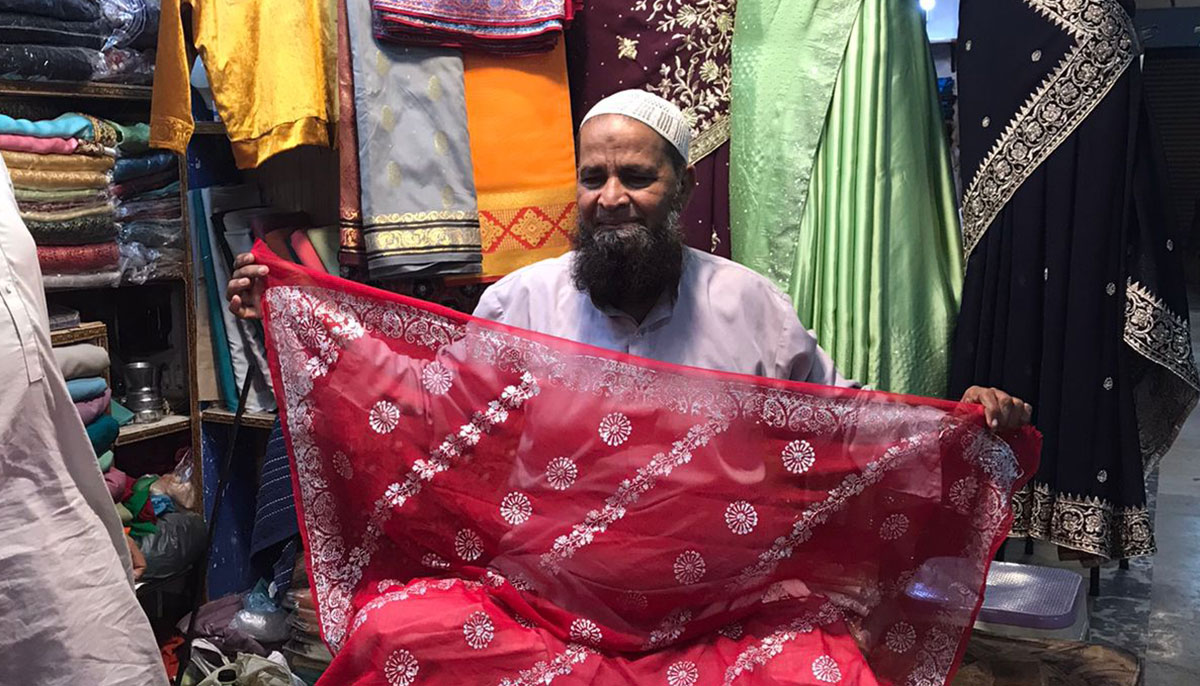 Chaapa fabric seller Jamal showing a chaapa sari at his shop in the Hyderi market, Karachi. — Photo by author