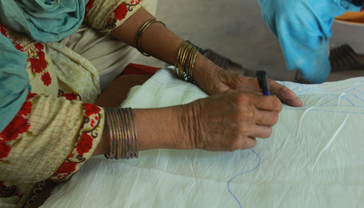 Allah Wasaai draws a design on a fabric using a pen to create the chunari affect. &mdash; Photo by author