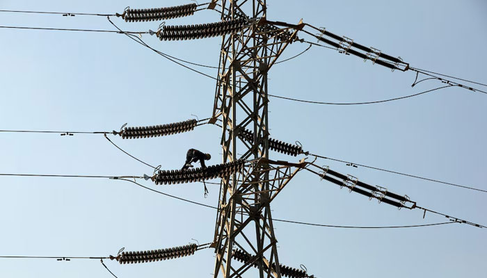 A technician works on porcelain insulators on power transmission tower in Karachi. — Reuters/File