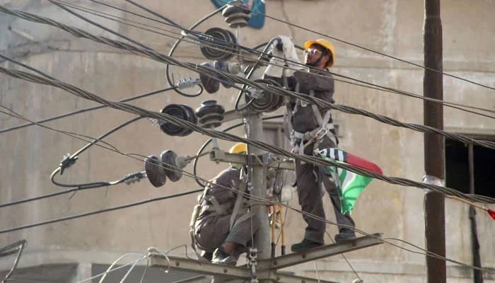 Technicians working on an electricity pole in this undated image. — Online