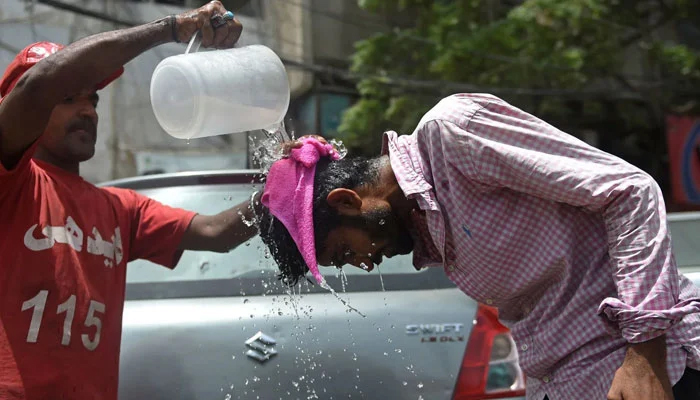 An Edhi volunteer pours water on a pedestrian along a street during a hot summer day in Karachi on May 16. — AFP/File