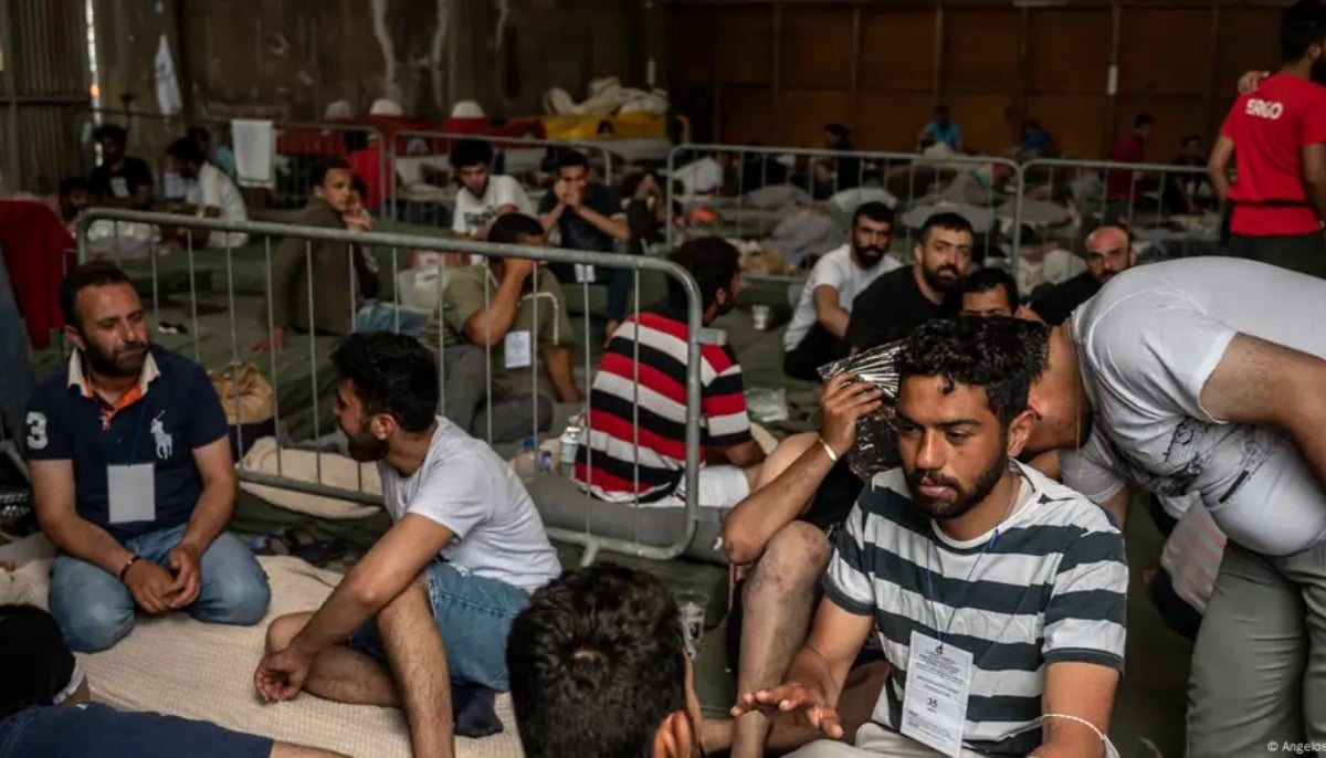 Survivors of a shipwreck sit inside a warehouse at the port in Kalamata town, on June 15, 2023, after a boat carrying migrants sank in international waters in the Ionian Sea. — AFP