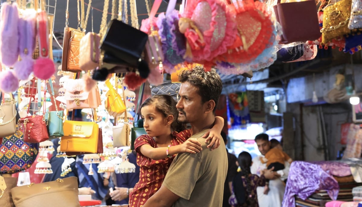 A man and a girl, look at handbags on display outside shops, ahead of Eid ul Fitr celebrations in Karachi on March 29, 2025. — Reuters
