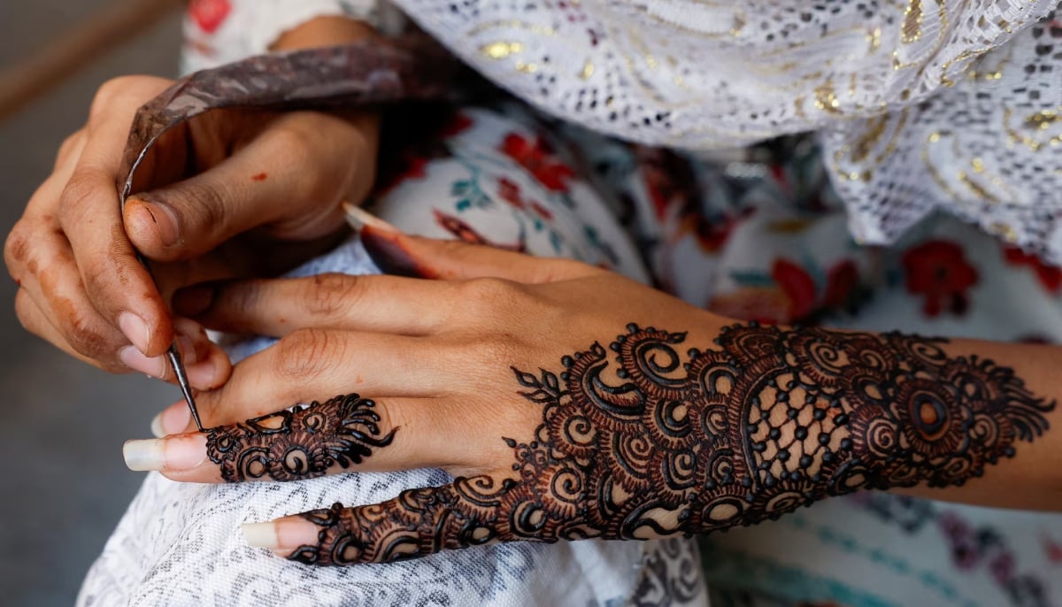 A girl applies henna patterns on her hands while waiting for customers, ahead of Eid ul Fitr celebrations, in Karachi on April 9, 2024. — Reuters