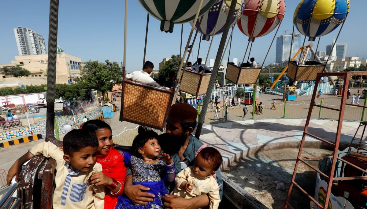 Abdul Karim, 26, father of four, sits with his children as they ride on a carousel, during the third and last day of the Muslim holiday Eid ul Fitr in Karachi, Pakistan June 7, 2019. — Reuters