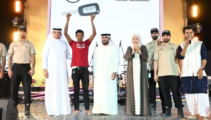 A participant poses with his prize alongside officials from the government of Dubai  during a grand Eid celebration event for workers in Dubai, UAE. — Reporter