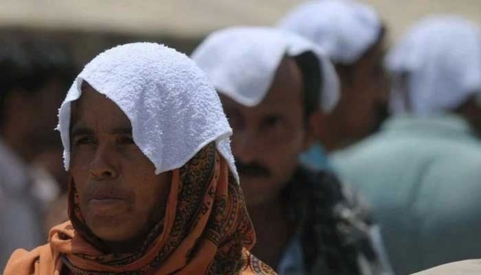 People with their heads covered with wet towels during a heatwave in Karachi. — AFP/File