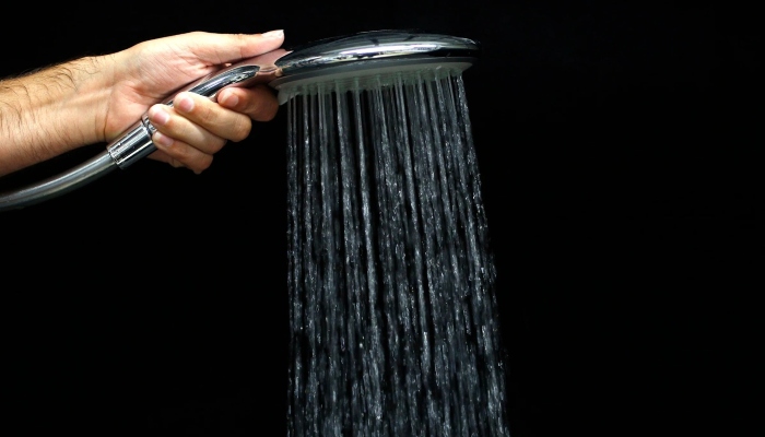This representational image shows a person holding a showerhead. — Reuters
