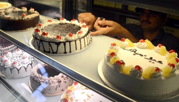 On the eve of Eid ul Fitr a worker displaying Eid cakes to attract the customers at a bakery, Islamabad, March 30, 2025. — INP