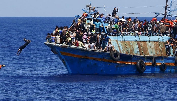 A migrant dives into the water from an overloaded wooden boat during a rescue operation 10.5 miles (16 km) off the coast of Libya, August 6, 2015. — Reuters