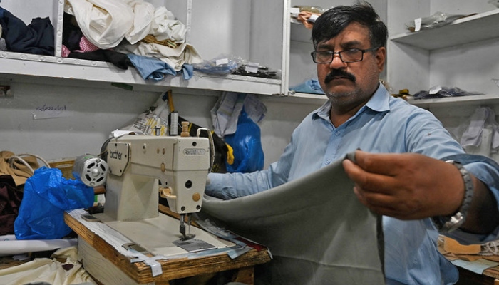 A tailor stitches a fabric at his shop in Islamabad on April 29, 2022. —AFP