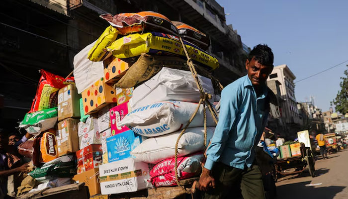 A labourer reacts as he transports a cart full of sacks at a wholesale market in the old quarters of Delhi, India. — Reuters/File