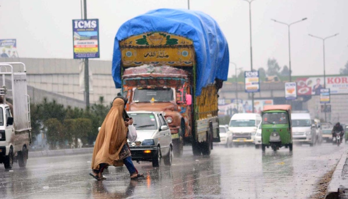Women crossing the road during rain in Peshawar, on February 25, 2025. — APP