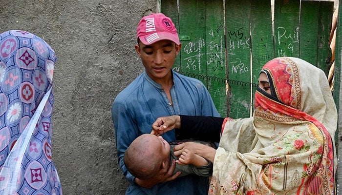 This photograph taken on October 5, 2024, shows a health worker (right) administering polio drops to a child during a door-to-door poliovirus vaccination campaign in the outskirts of Peshawar. — AFP