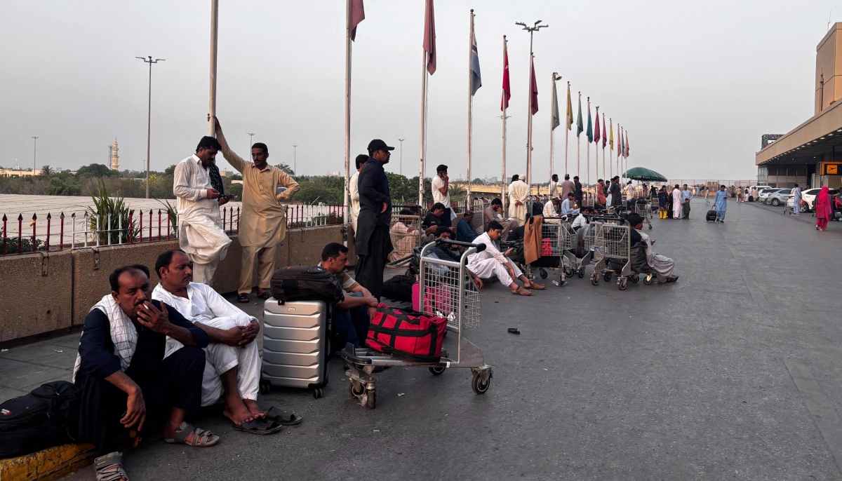 Passengers wait outside at Jinnah International Airport after all domestic and international flights were cancelled in Karachi on May 7, 2025. — AFP