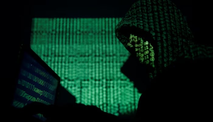 A hooded man holds a laptop computer as cyber code is projected on him in this illustration picture taken on May 13, 2017. — Reuters