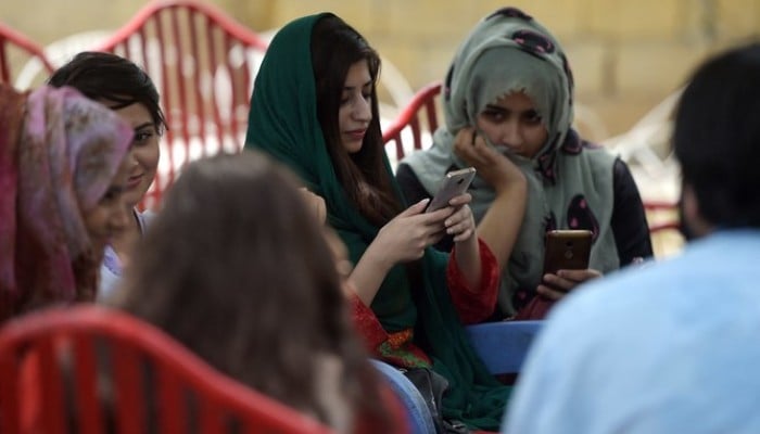 Students use their mobile phones at a campus in Islamabad on July 12, 2018, — AFP