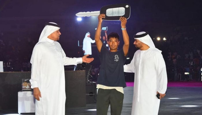 A worker raises a placard of a car key during Eid ul Adha celebrations titled Lets Celebrate Eid Together  in Dubai. — Reporter
