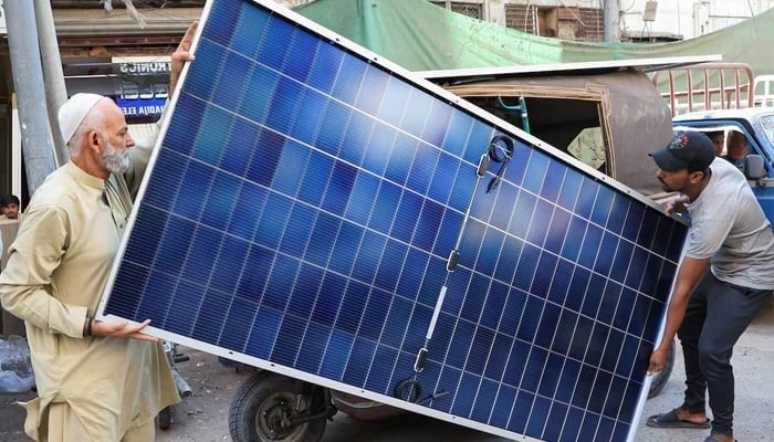 Men load solar panels on a rickshaw at a market in Karachi, on March 26, 2025. — Reuters