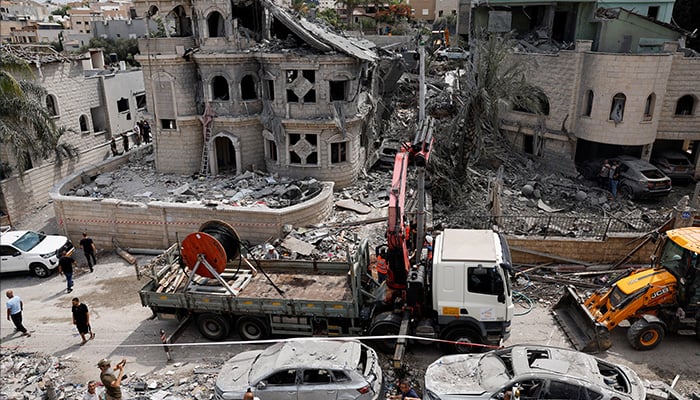 People stand next to a damaged vehicle after missiles fired from Iran impacted a residential building, in Tamra, northern Israel June 15, 2025. — Reuters