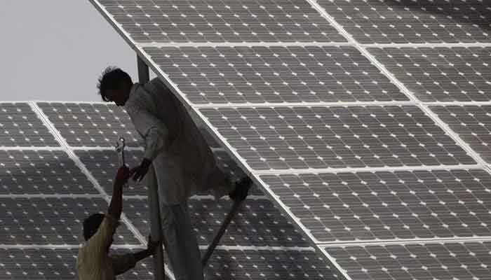 Technicians work on a solar panel at a power station about 25 km from Karachi June 18, 2010. — Reuters