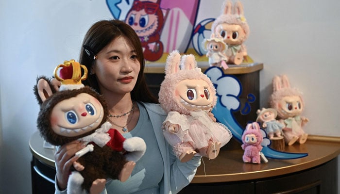 A woman poses with Labubu (L) and Mokoko characters in an exhibition hall as they visit Pop Mart theme park Pop Land in Beijing, China on June 18, 2025. — AFP