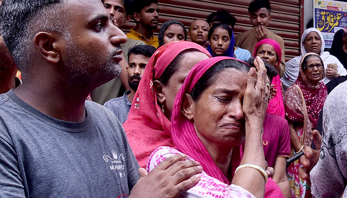 Grief-stricken family members break down in tears at the tragic site of a collapsed residential building in Baghdadi, Lyari. — APP/File