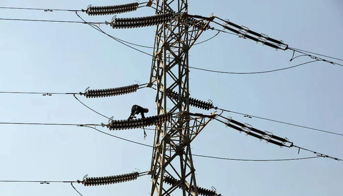A technician works on porcelain insulators on power transmission tower in Karachi. — Reuters/File