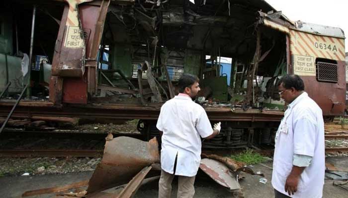 Forensic officers examine a damaged railway train compartment hit by bomb blast in Mumbai July 12, 2006. — Reuters