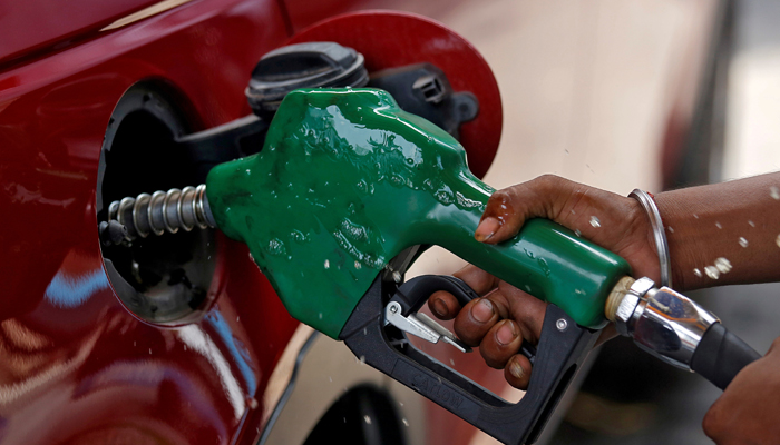 A worker holds a nozzle to pump petrol into a vehicle at a fuel station. — Reuters
