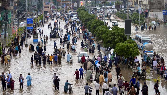 People wade through a flooded road after the monsoon rain in Karachi, Pakistan, August 19, 2025.&nbsp;&mdash; Reuters