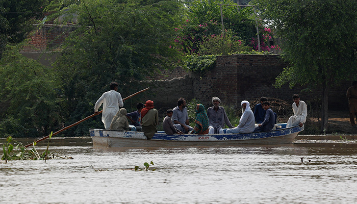 A resident carries milk buckets as he crosses a flooded road, due to the monsoon rains and rising water level of the Sutlej River, in Bhikhiwind village, near the Pakistan-India border in Kasur district of the Punjab, August 24, 2025.  — Reuters
