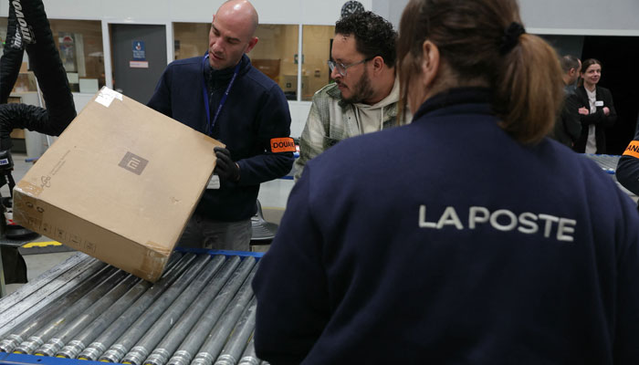 French Customs officers control postal parcels in the Customs area of the postal customs clearance office located in the sorting centre of La Poste, near Orly airport, South of Paris on March 20, 2025. — AFP