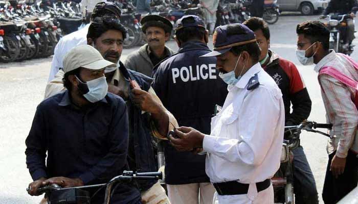 Traffic police staff issuing challan to people riding bikes without a helmet in Karachi.— PPI