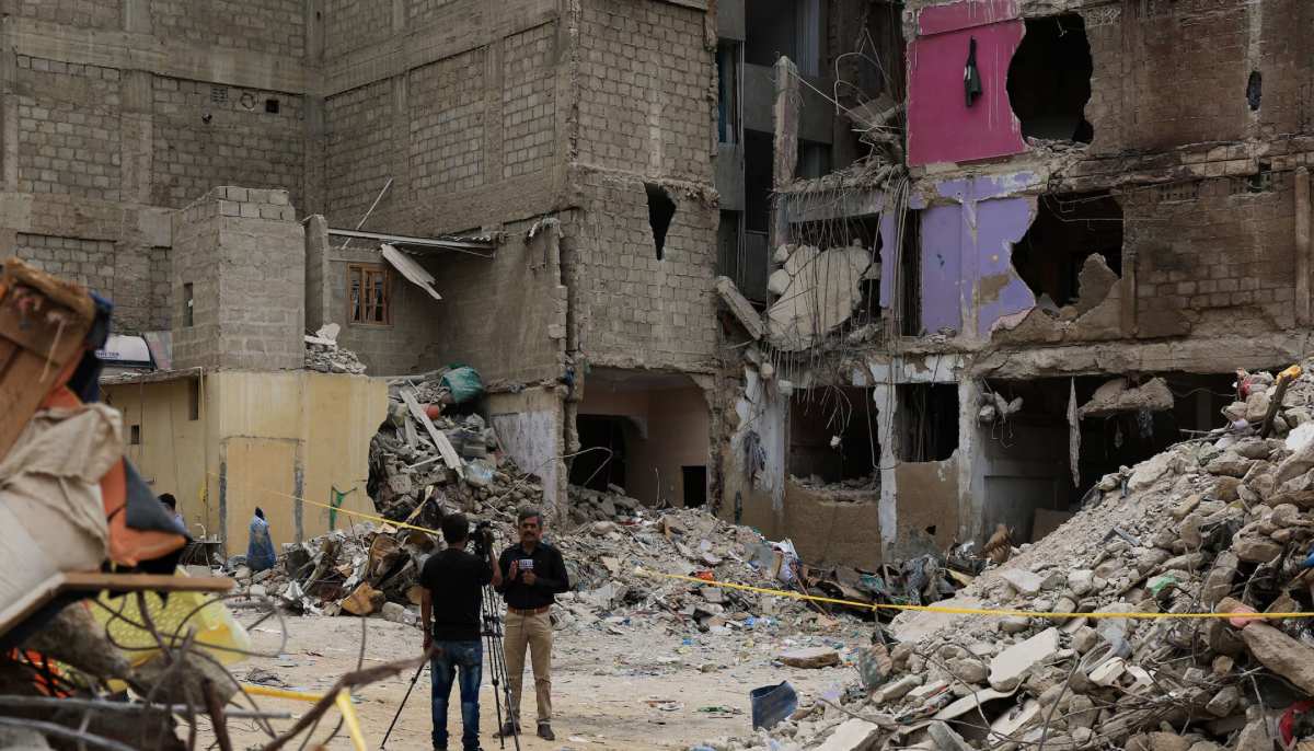Members of the media report from the ground near a five-storey residential building that collapsed in Karachi on July 7, 2025. — Reuters
