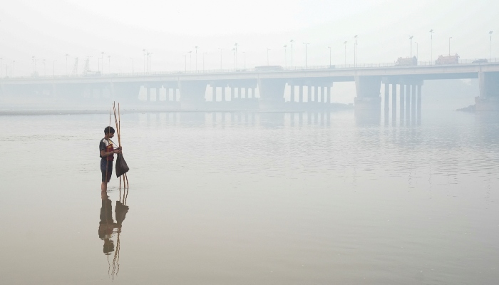 Faheem sets up a fishing trap, with the bridge over the River Ravi in the background, amid smog in Lahore, Pakistan, November 5, 2024. — Reuters