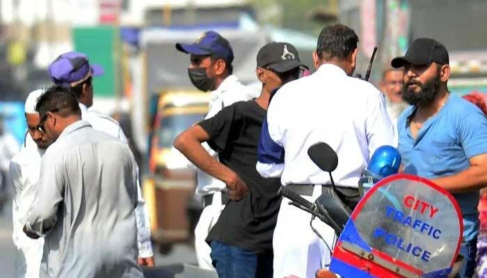 Traffic police officials charge a challan for violating the traffic rules at Saddar area in Karachi. — PPI
