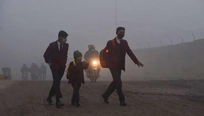 Children walk to their school along a street amid smoggy conditions. — AFP