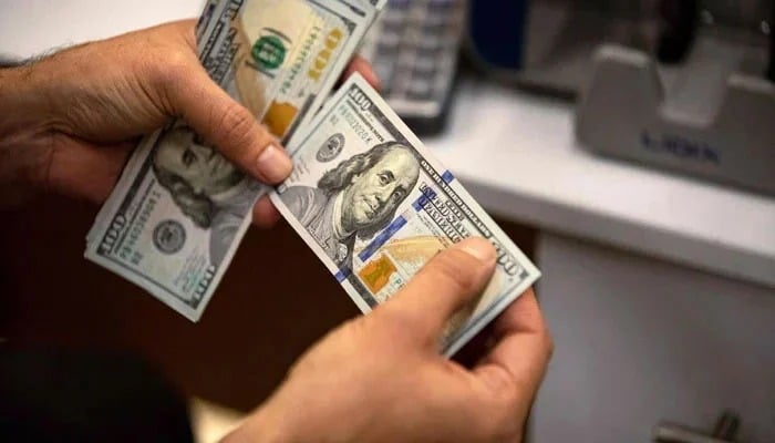 Representational image shows a currency exchange agent counting US dollars at his company. — AFP/File