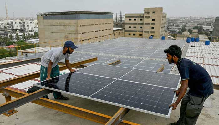 Technicians install solar panels on the rooftop of a factory in Karachi on  July 2, 2025. — AFP