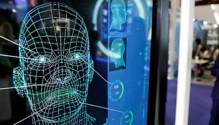Visitors check their phones behind the screens advertising facial recognition software during Global Mobile Internet Conference at the National Convention in Beijing, China. — Reuters/File