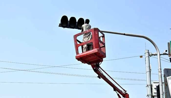 Worker is busy installing new traffic signals in this undated image. — APP
