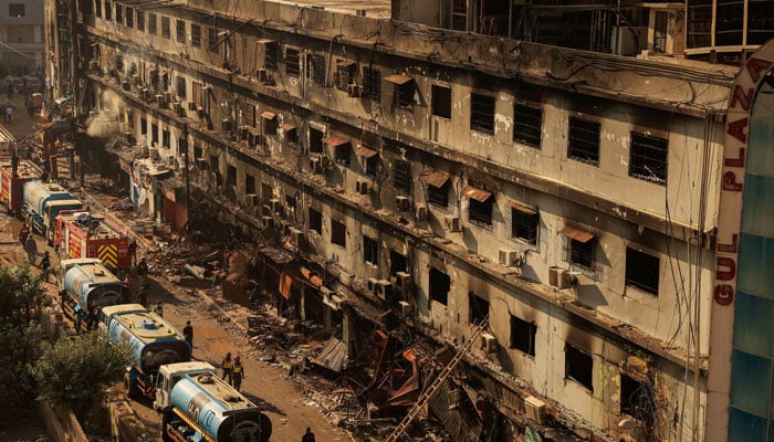 Fire department workers walk past the site, following a massive fire that broke out in the Gul Plaza Shopping Mall in Karachi, January 20, 2026. — Reuters