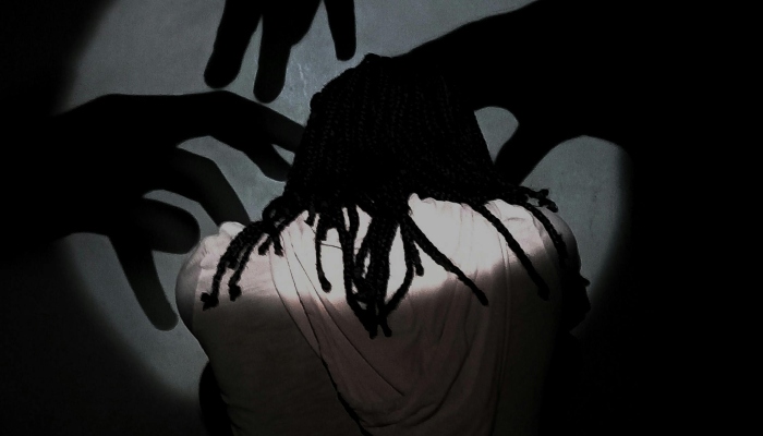 Backview of a person with shadows on the wall representing intrusive thoughts. — Pexels