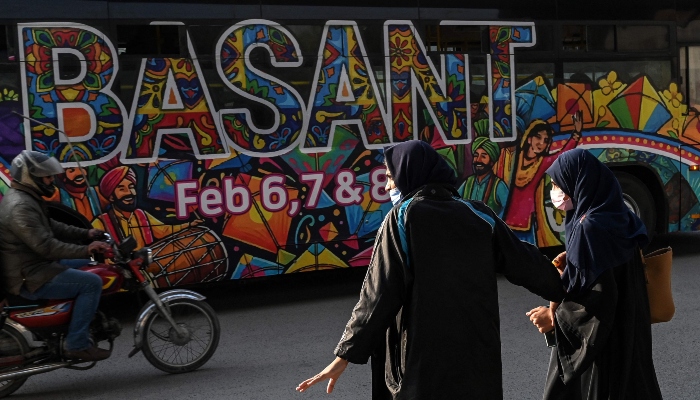 Women walk past a bus decorated with the theme of the Basant Festival in Lahore on February 5, 2026. — AFP