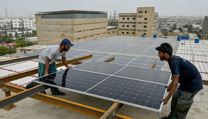 Technicians install solar panels on the rooftop of a factory in Karachi on  July 2, 2025. — AFP